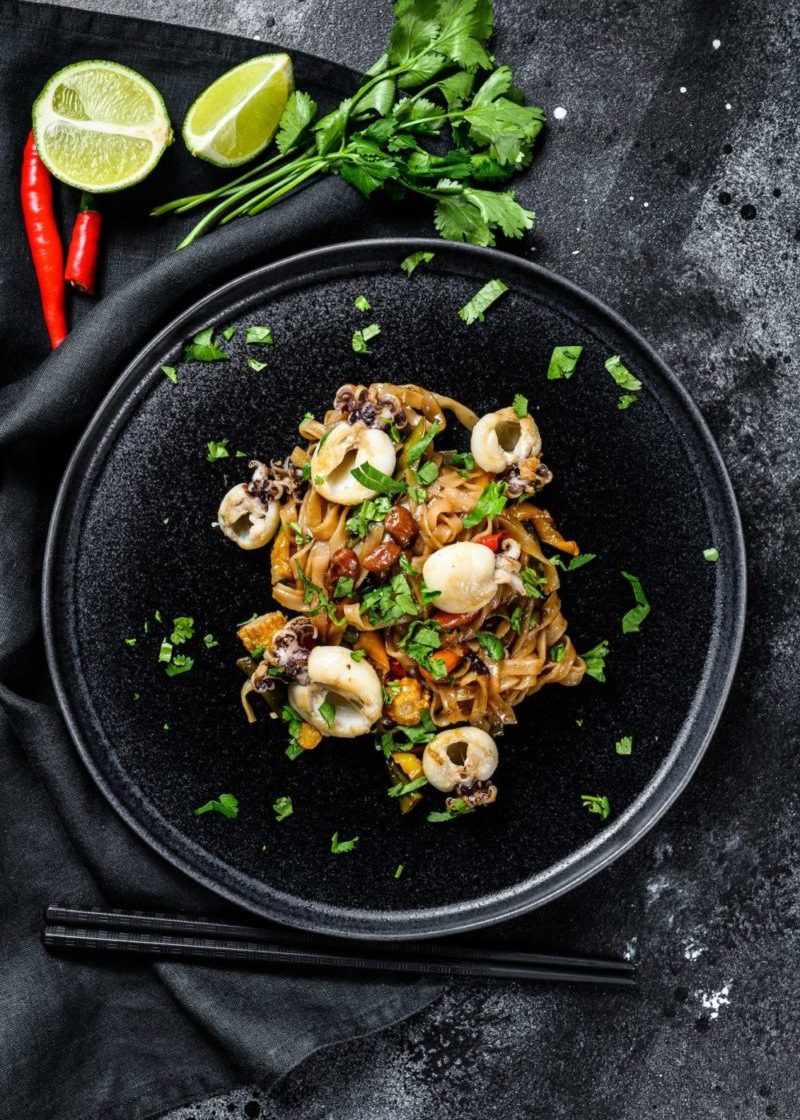 homemade-stir-fry-damage-noodles-with-seafood-and-vegetables-in-a-plate-black-background-top-view-e1679147684828-q3p66ku20lkt9f2mdpu9e7yvmj6dy7g3cez9f0wp8g